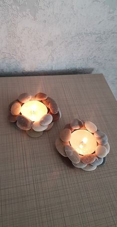 two candles are sitting on a table with flowers in the shape of petals and leaves