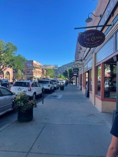 cars parked on the side of a street next to shops and restaurants in an urban setting