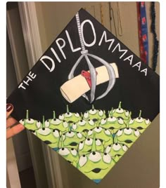 someone is holding up a graduation cap with the words diploma in front of them and cartoon faces on it