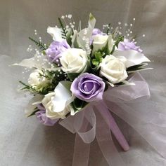 a bridal bouquet with white and purple flowers on a gray clothed tablecloth