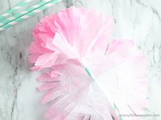 pink tissue paper flowers and straws on a marble countertop with mint green straws