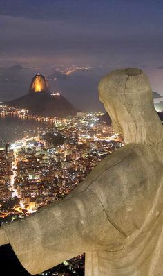 a statue overlooking the city lights at night