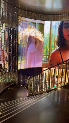 a woman is walking down the stairs in front of a large screen