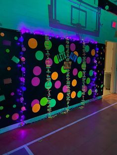 an indoor basketball court is decorated with neon lights and streamers on the side wall