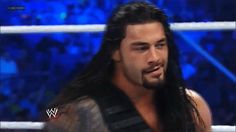 a man with long hair standing next to a wrestling ring