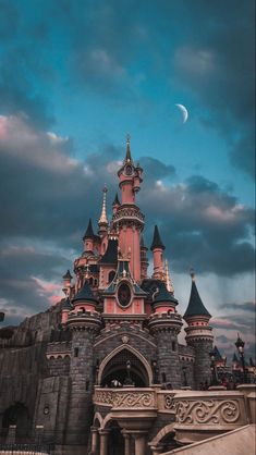 the castle is pink and has turrets on it's roof, with a moon in the background