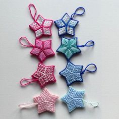 four small crocheted stars are shown on a white surface, one is blue and the other is pink