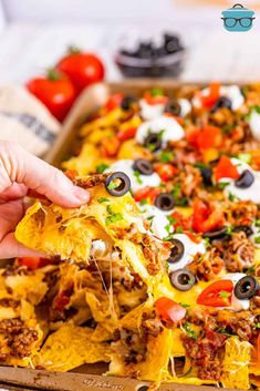 a person is taking a piece of nachos out of the box