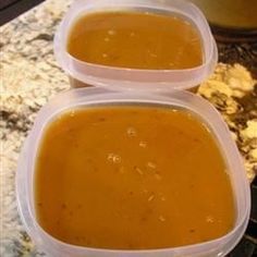 two plastic containers filled with soup sitting on top of a counter next to an oven