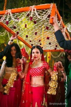 two women dressed in red and gold are posing for the camera while another woman is holding her hand up