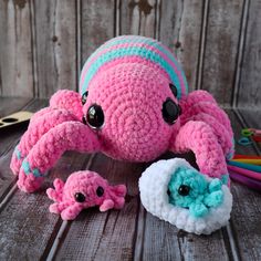 a crocheted pink and blue crab with two smaller crabs in front of it