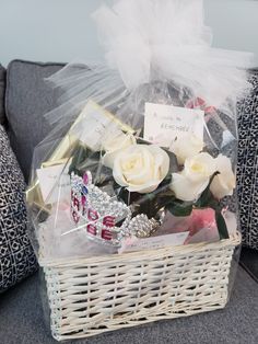 a basket filled with white roses on top of a couch next to pillows and a pillow