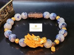 Gift yourself or your loveonce this beautiful exquisite Pure Gold Dragon Bracelet.  *Materials: Au999 Pure Gold, Dumortierite, and Obsidian Stone.  *Karat: 24K Pure Gold  *Gold Color: Yellow *Stone Size: 10mm *Gold Mass: Approximately 4.22g *Dragon length:  Approximately 1.09 Inch *Tibetan Dzi Stone: Approximately 10x22mm 💢 The dragon ia the male element of yang, it represents good luck, fortune, strength, and health. ●Metal is made of Pure Gold only. NOT gold filled, NOT Gold plated, NOT gold vermeil. Hollow. Hallmarked.  💥PLS FOLLOW US AND CHECK OUR OTHER LISTINGS. WE HAVE NEW STOCKS LISTED DAILY/WEEKLY.  📬S H I P P I N G WE SHIP WITHIN 24 HOURS. Free shipping in the US and International orders. Gold Spiritual Crystal Bracelet For Wedding, Gold Spiritual Crystal Bracelet For Gift, Spiritual Gold Bracelet With Round Beads As Gift, Gold Bracelet With Round Beads For Birthday Gift, Gold Beaded Bracelet For Birthday Gift, Luxury Gold Bracelet With Round Beads For Gift, Luxury Bracelets For Festivals As Gifts, Luxury Bracelets For Festivals Gift, Luxury Gold Beaded Bracelet For Gift