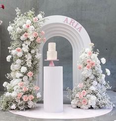 a wedding cake sitting on top of a white pedestal surrounded by pink and white flowers