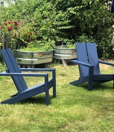 two lawn chairs sitting on top of a lush green field next to a metal tub