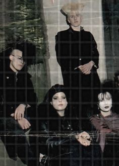 the group of people are dressed up in black and posing for a photo with their faces painted white