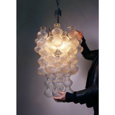 a person holding a light fixture made out of glass balls