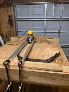 a work bench with a sanding machine on it's side and a garage door in the background