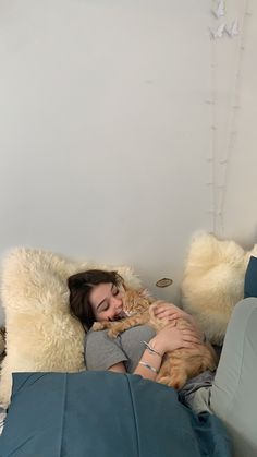 a woman laying on top of a bed with a cat in her lap next to pillows