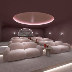 a room with couches, tables and lights on the ceiling is lit by dim lighting