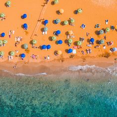 an aerial view of the beach with umbrellas and people laying on top of it