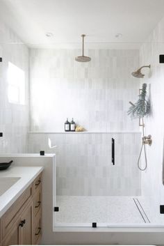 a bathroom with a walk in shower next to a white sink and wooden cabinetry