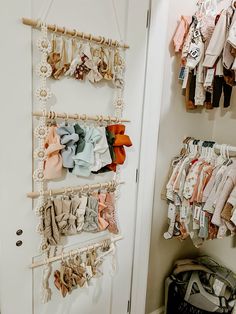 there is a rack with baby clothes hanging on the wall next to an open door