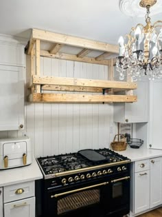 a stove top oven sitting under a chandelier in a kitchen next to white cabinets