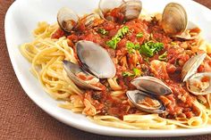 a white plate topped with pasta and clams