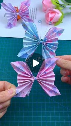 two hands are holding origami butterflies