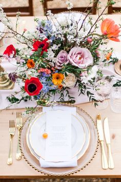 a vase filled with flowers sitting on top of a table next to plates and silverware