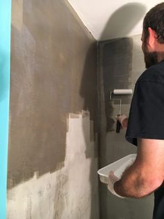 a man in black shirt painting walls with white paint on the wall and blue trim