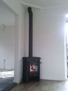 a wood burning stove in the corner of a room with white walls and hardwood floors