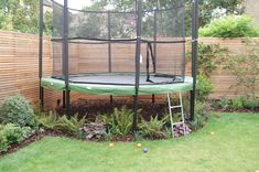 a green trampoline in the middle of a yard with a ladder up to it