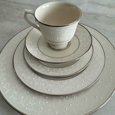 a stack of white plates and cups on top of each other with silver trimmings