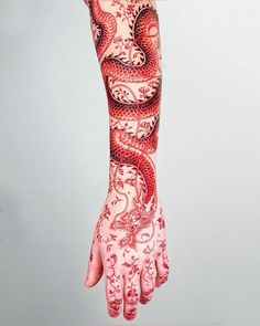 a woman's arm and hand covered in red ink with an intricate dragon design