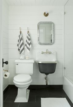 a white toilet sitting next to a sink in a bathroom on top of a black and white floor