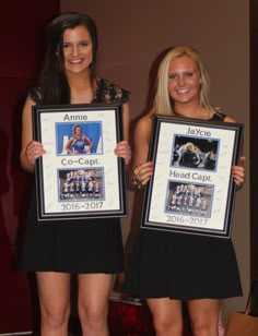 two women standing next to each other holding framed pictures