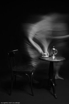 a blurry photo of a person sitting at a table with a teapot on it