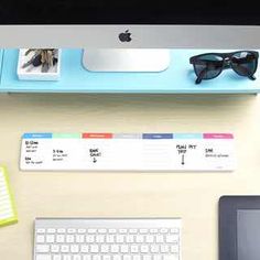 a desk with a keyboard, mouse and sunglasses on it next to a computer monitor