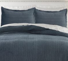 a bed with blue and white bedspread, pillows and blankets on top of it