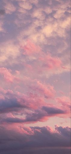 an airplane is flying in the sky with pink clouds