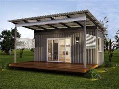 a small house made out of shipping containers in the middle of a grassy area with a covered patio