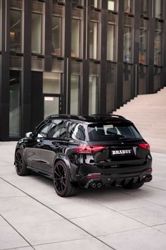 a black car parked in front of a tall building