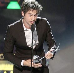 the young man is holding his award for outstanding performance in a musical role or play