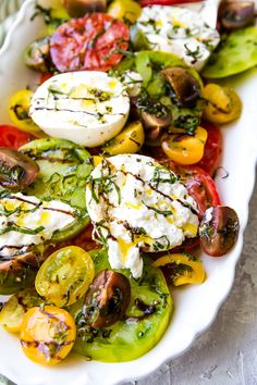 a white platter filled with lots of different types of veggies and cheese