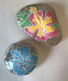 two painted rocks sitting on top of a white surface