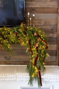 a christmas garland with lights on it and a flat screen tv mounted above the mantel