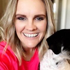 a woman smiling while holding a dog in her lap