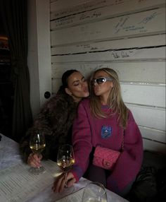 two women sitting at a table with wine glasses